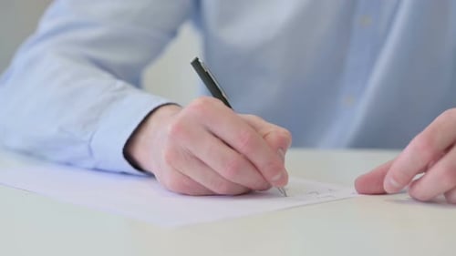 Nahaufnahme eines jungen Mannes, der auf Papier schreibt