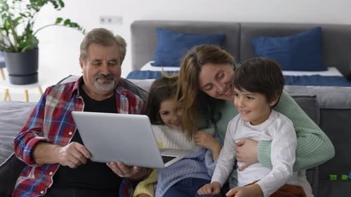 Family Uses Laptop Together at Home on Couch