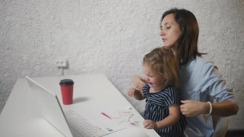 Woman Works in Office with a Naughty Child. Young Woman Calms Crying Child in Office.