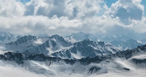 Air Flight Through Mountain Clouds Over Beautiful Snowcapped Peaks of Mountains and Glaciers