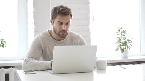 Bearded Man Working on Laptop at Desk