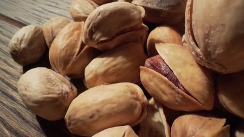 Pile of delicious pistachios on a wooden surface