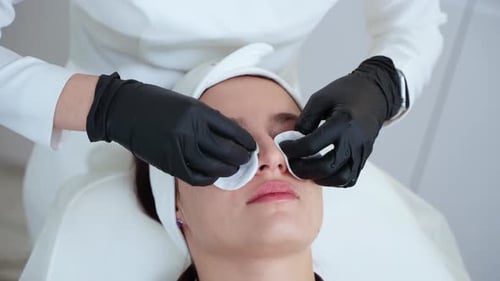 Adult Woman is Relaxing in Spa Salon During Skincare Treatment Aesthetician is Wiping Face Skin