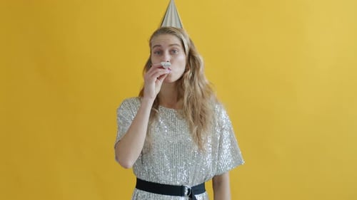 Woman Celebrates with Noisemaker Against Yellow Background