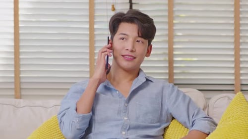 Young Man Answering Phone on Couch Indoors