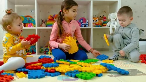 Children Play Together With Building Blocks in Playroom