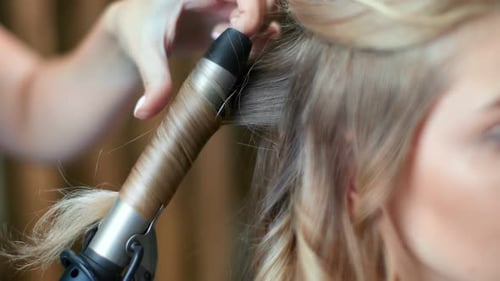 Closeup Hands of Hairdresser Creating Hairdo Use Curling Iron