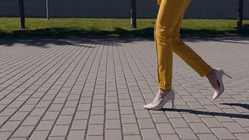Female slim legs in high heels shoes walking in the urban street