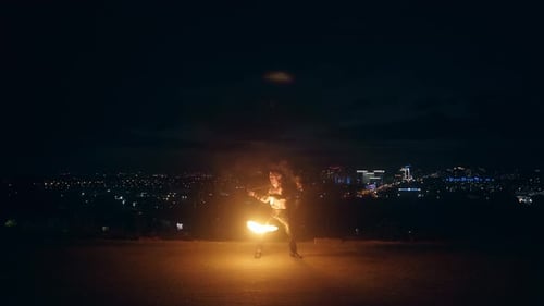 Man Juggling Fire Sticks at Night in City