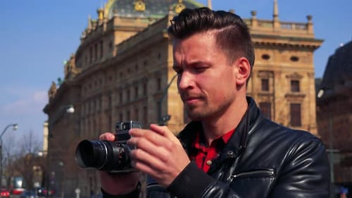 A Young Handsome Man Takes Photos with a Camera - an Old Building of a Quaint Town