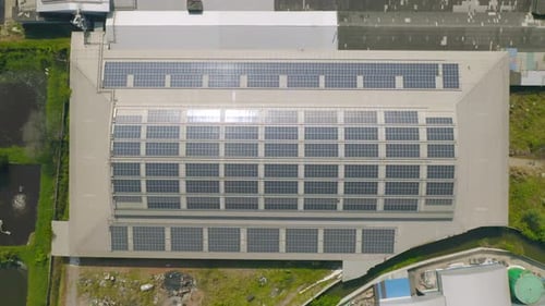 Aerial view of solar panels or solar cells on the roof of factory building rooftop. Power plant