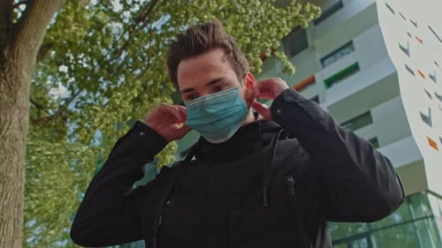 Man Puts On Blue Face Mask Outside