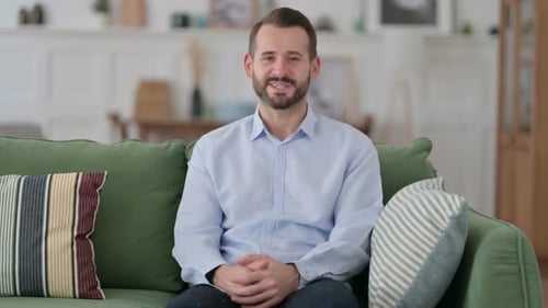 Adult Man Sitting on Couch Talking and Waving