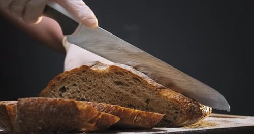 Gloved Hand Slices Warm Fresh Bread
