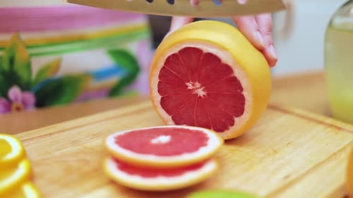 Woman Slices Grapefruit in Bright Kitchen