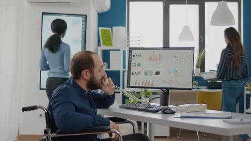 Man in Wheelchair Works at Desk in Office