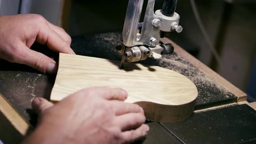 Man Carving Wood with Saw in Workshop