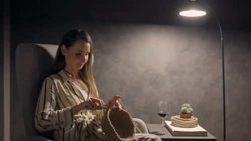 Woman Knitting by Lamp Light in Armchair