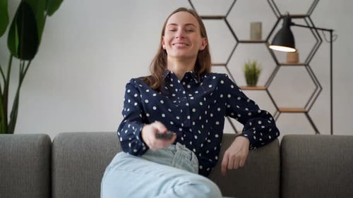 Smiling Woman Changing Channels on Remote in Living Room
