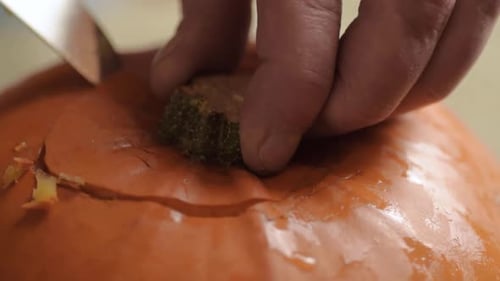 Removing top from a ripe fresh pumpkin with a knife