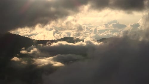 Wolkenschichten in bewaldeten Bergen am Morgen