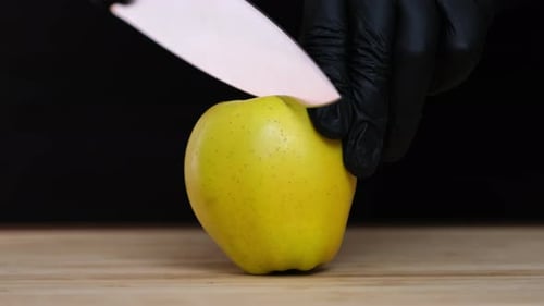 One apple lies on cutting board. Large kitchen knife cuts a apple
