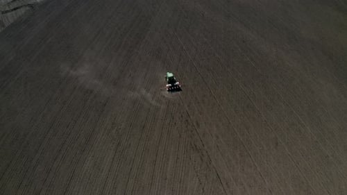 Feld mit malerischen Hügeln und einem fahrenden Traktor