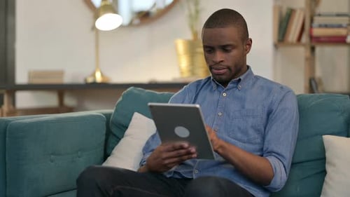 Young Man Relaxing on Couch Using Tablet