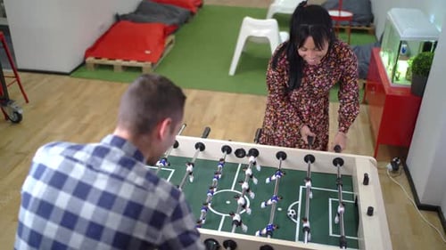 Man and Woman Playing Table Football in Office