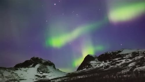 Majestic Northern Lights Display Above Snow-Capped Peaks