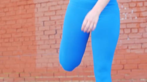 Athletic Woman Stretching Quads Against Brick Wall