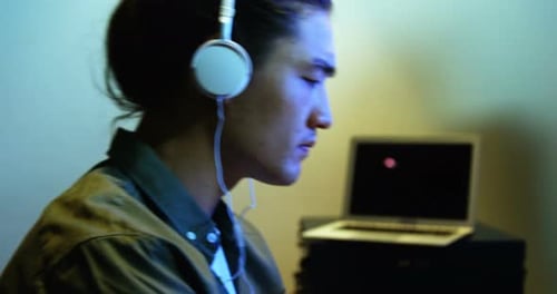 Male audio engineer listening to headphones while mixing sound