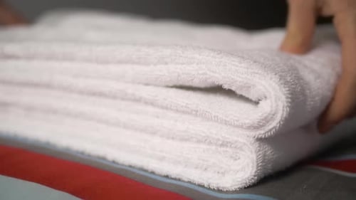 Close-up of Hands Putting Stack of Fresh White Bath Towels on the Bed Sheet. Room Service Maid