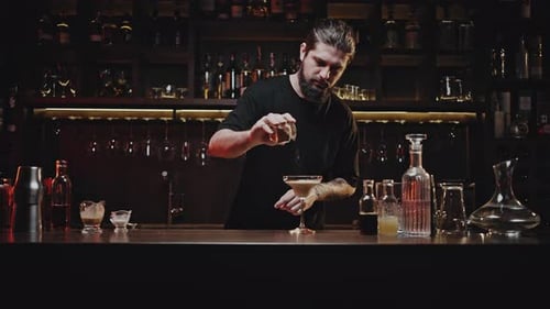 El camarero rocía el cóctel terminado con ingrediente seco