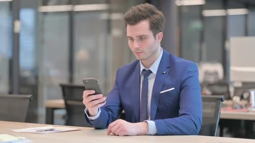 Attractive Businessman Using Smartphone in Office