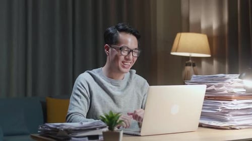 Smiling Man Working From Home on Laptop At Night
