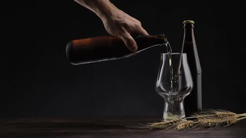 Hand Pours Refreshing Beer into Stemmed Glass