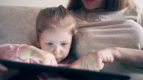 Child Using Tablet With Adult on the Couch