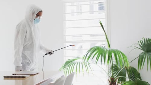 Health worker wearing protective clothes cleaning the office using disinfectant
