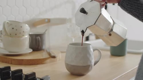Close Up of Woman Pouring Coffee into Mug in Kitchen