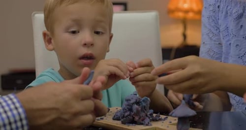 Child Sculpts Playdough with Family Assistance