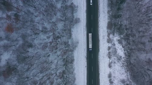 Aerial View of Traffic on the Road Passing Through the Winter Forest in Severe Weather