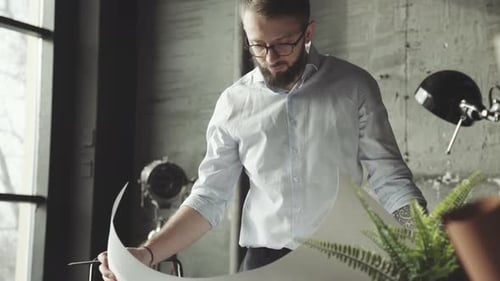 A Young Architect in a Stylish Office Working with Documents.