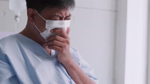 Sick Adult Coughing in Hospital Wearing Mask