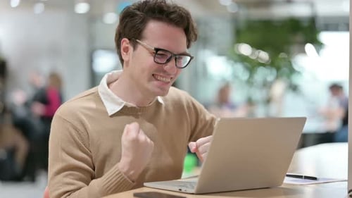 Young Male Designer with Laptop Celebrating in Office