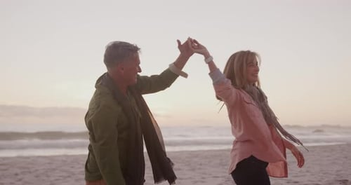 Active senior couple dancing on beach