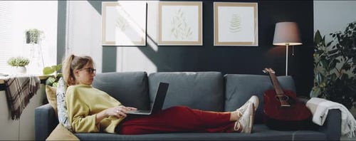 Woman Using Laptop Relaxing on Couch at Home