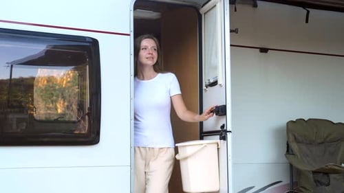Woman Standing in Doorway of White Caravan