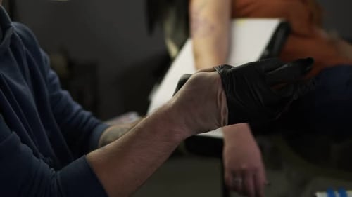 Close Up of Hands Tattoo Artist Putting on the Latex Black Gloves Before a Tattoo Session at the