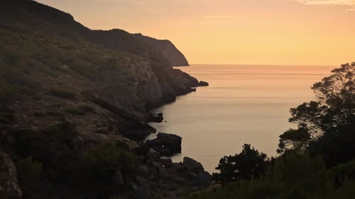 Exploring rocky mountain cliffs, cove beach at golden hour sunset, dolly